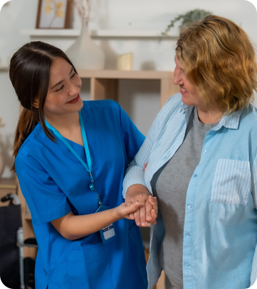 A nurse is holding the hand of an older woman.