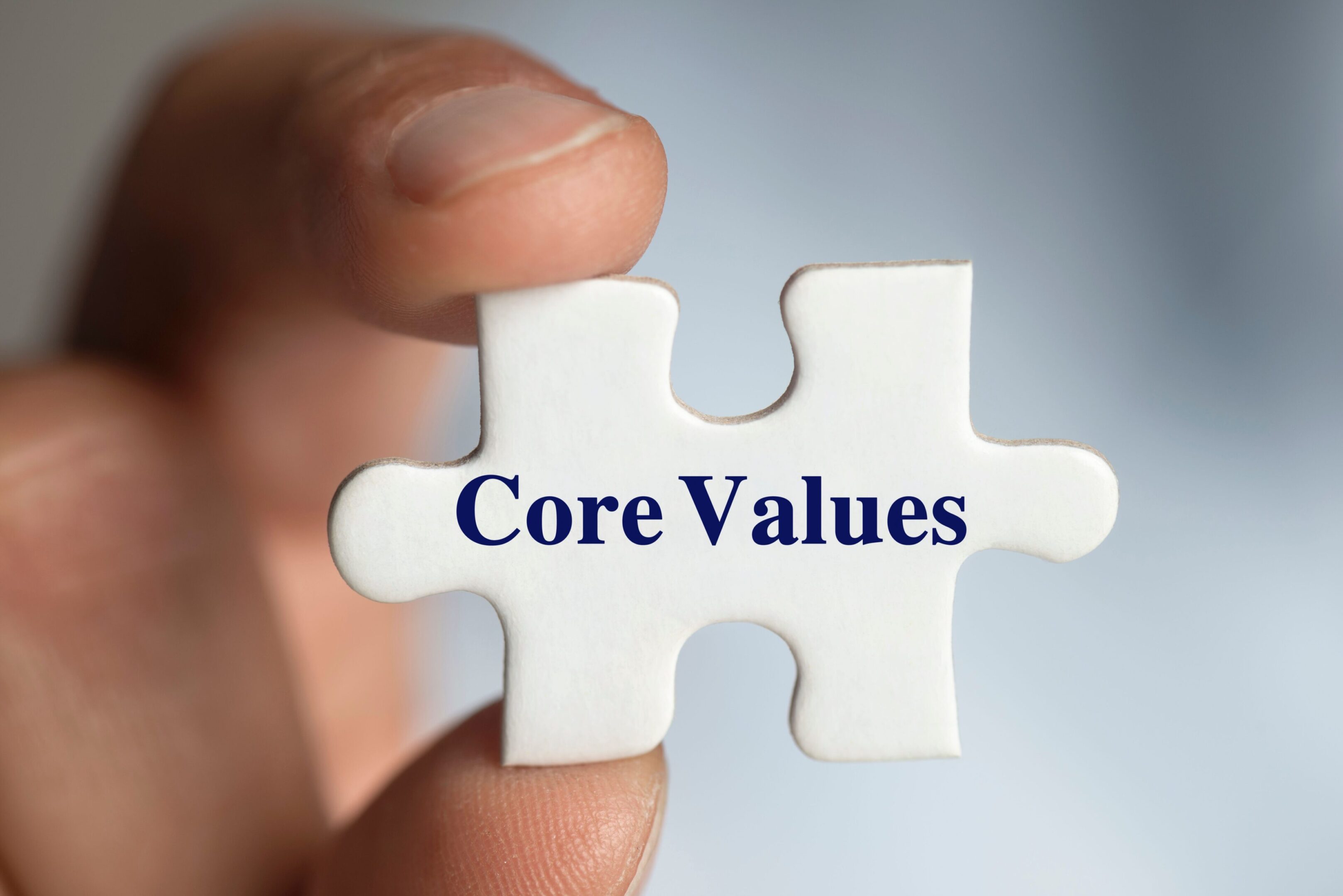 A person holding a puzzle piece with core values written on it.