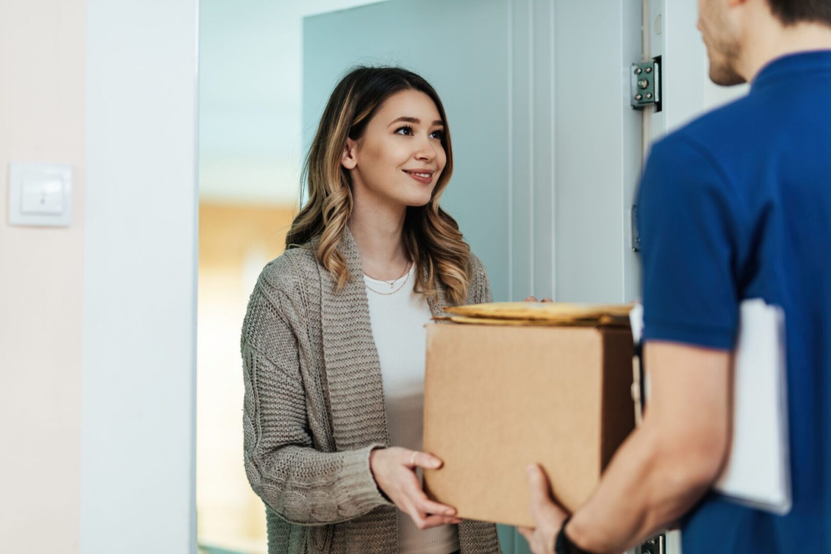 A woman holding a box in front of a man.