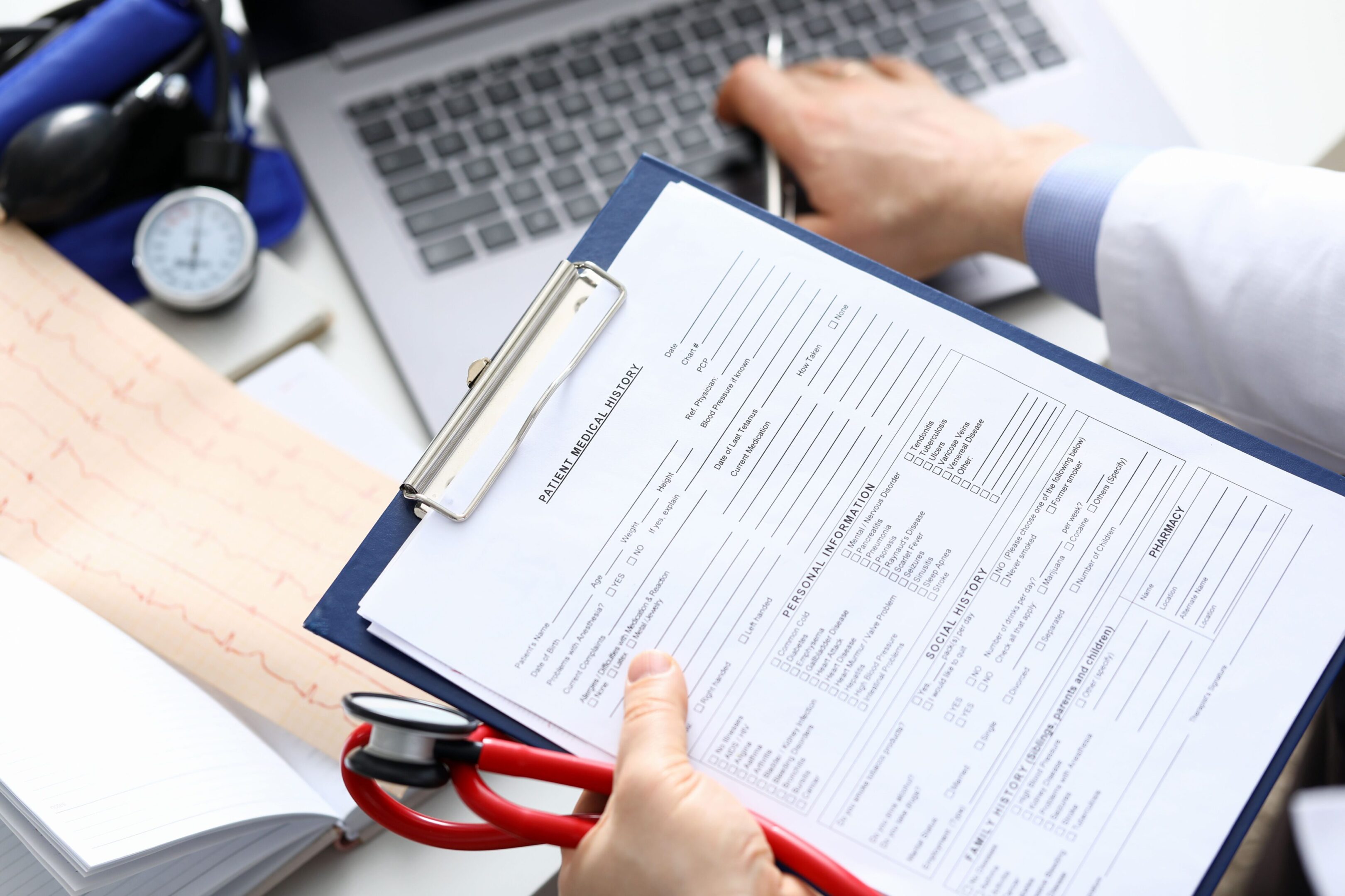 A person holding a clipboard and scissors over papers.