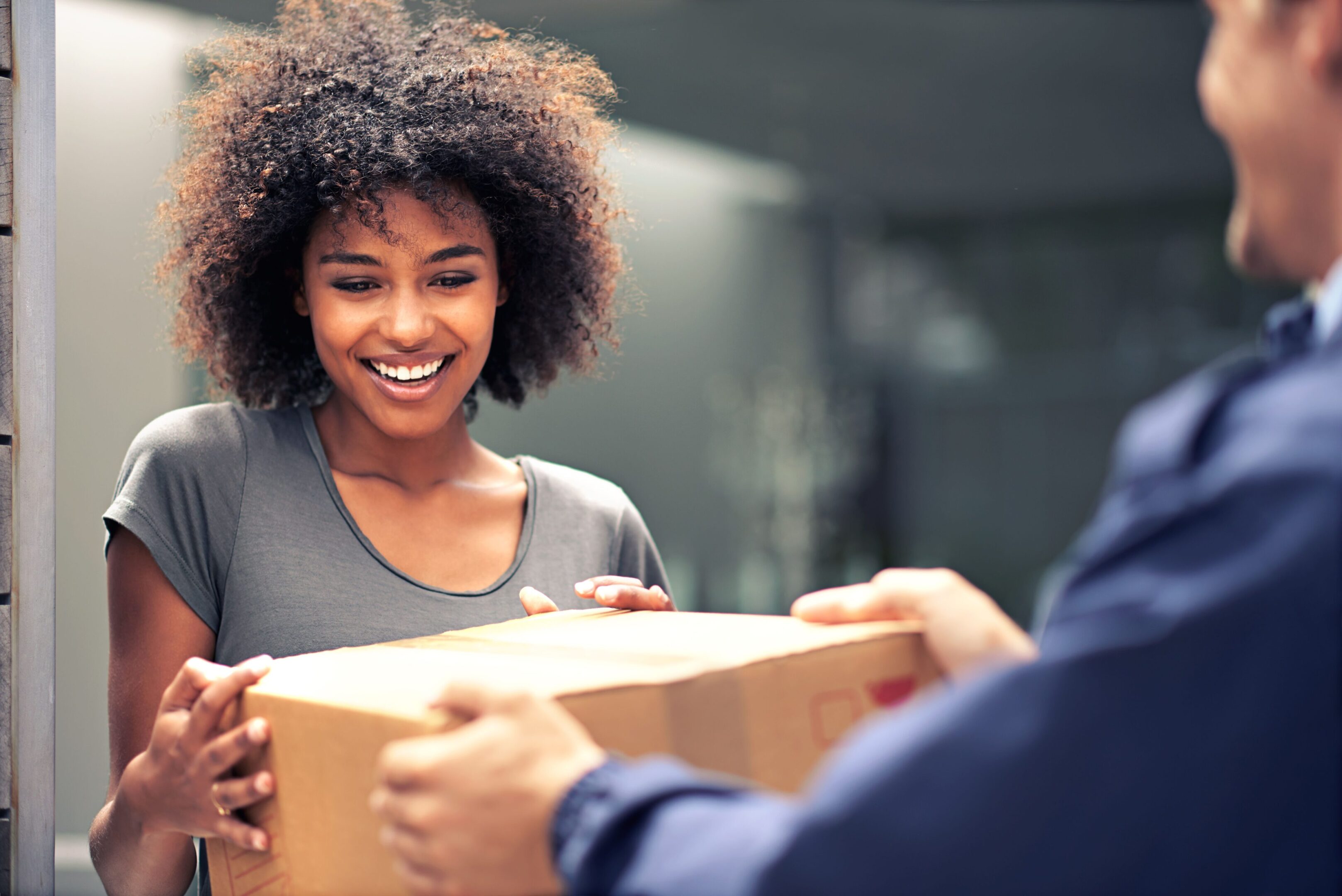 A woman smiles as she holds onto a box.