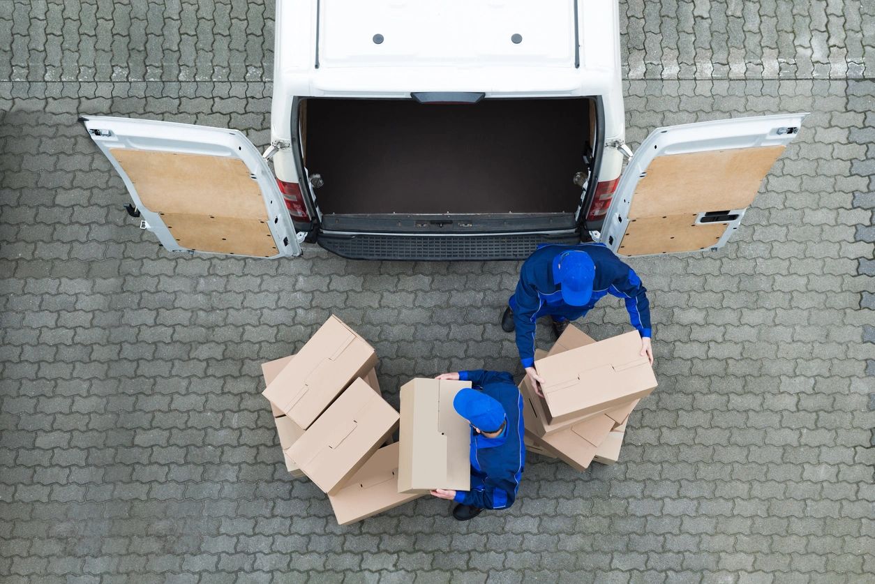 Two men unloading boxes from a van.